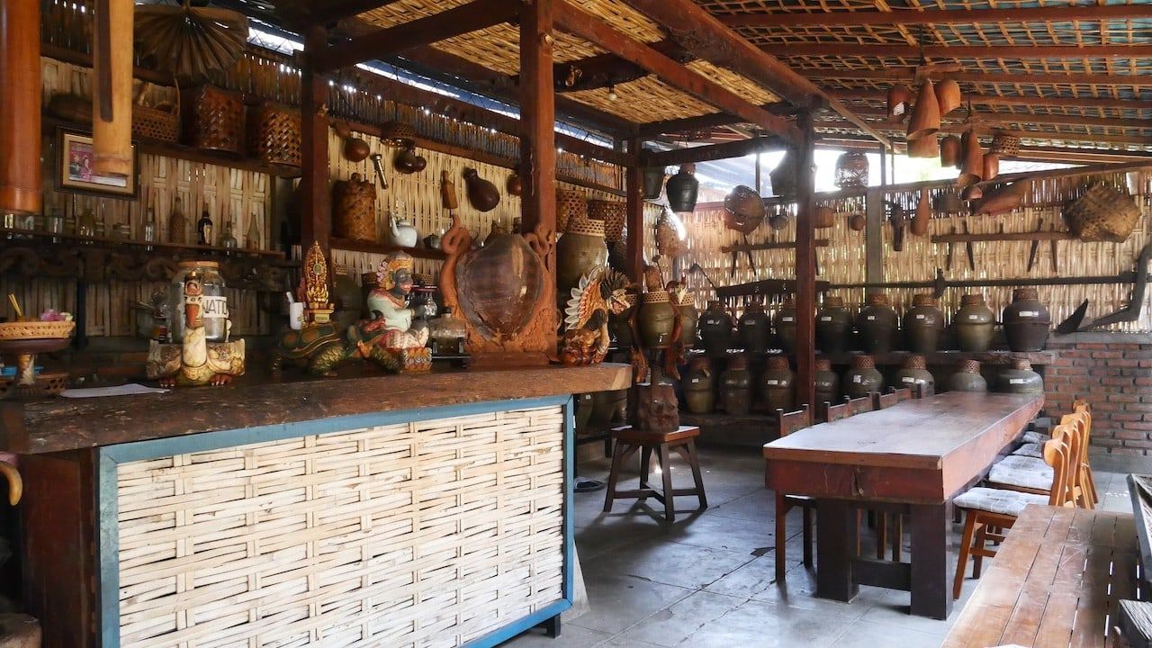 The open kitchen and long wooden table at Dapur Bali Mula, hung with traditional cooking tools