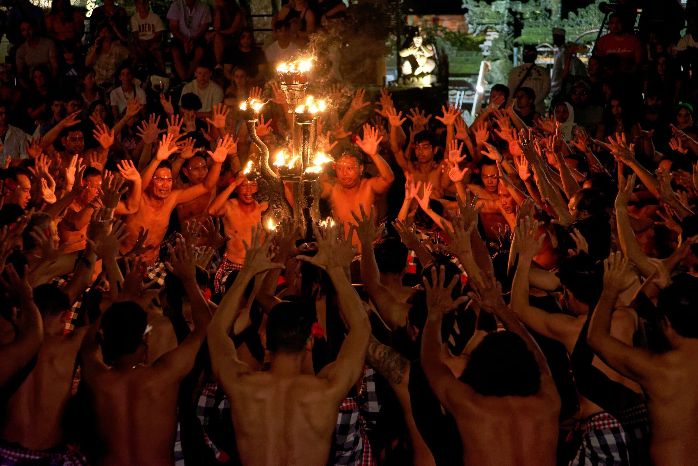 Kecak performers raising their hands around the fire in Ubud