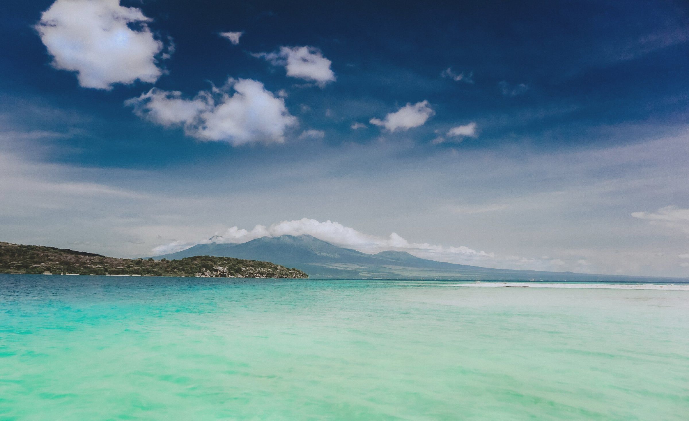 Turquoise shallows and white sand at Menjangan Island, with mountains beyond