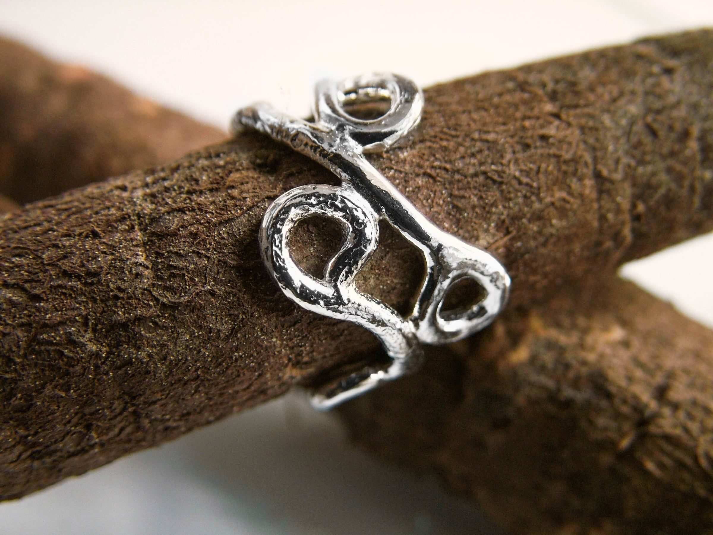 A handmade silver ring resting on a piece of wood