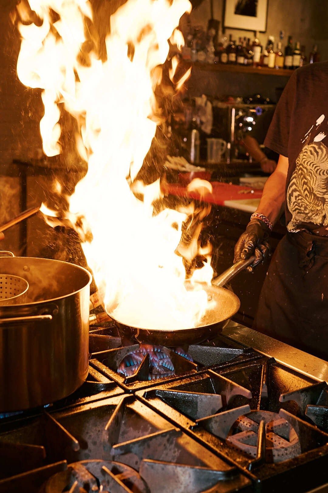Flames rising from a wok in the open kitchen at Wet Plate Kitchen