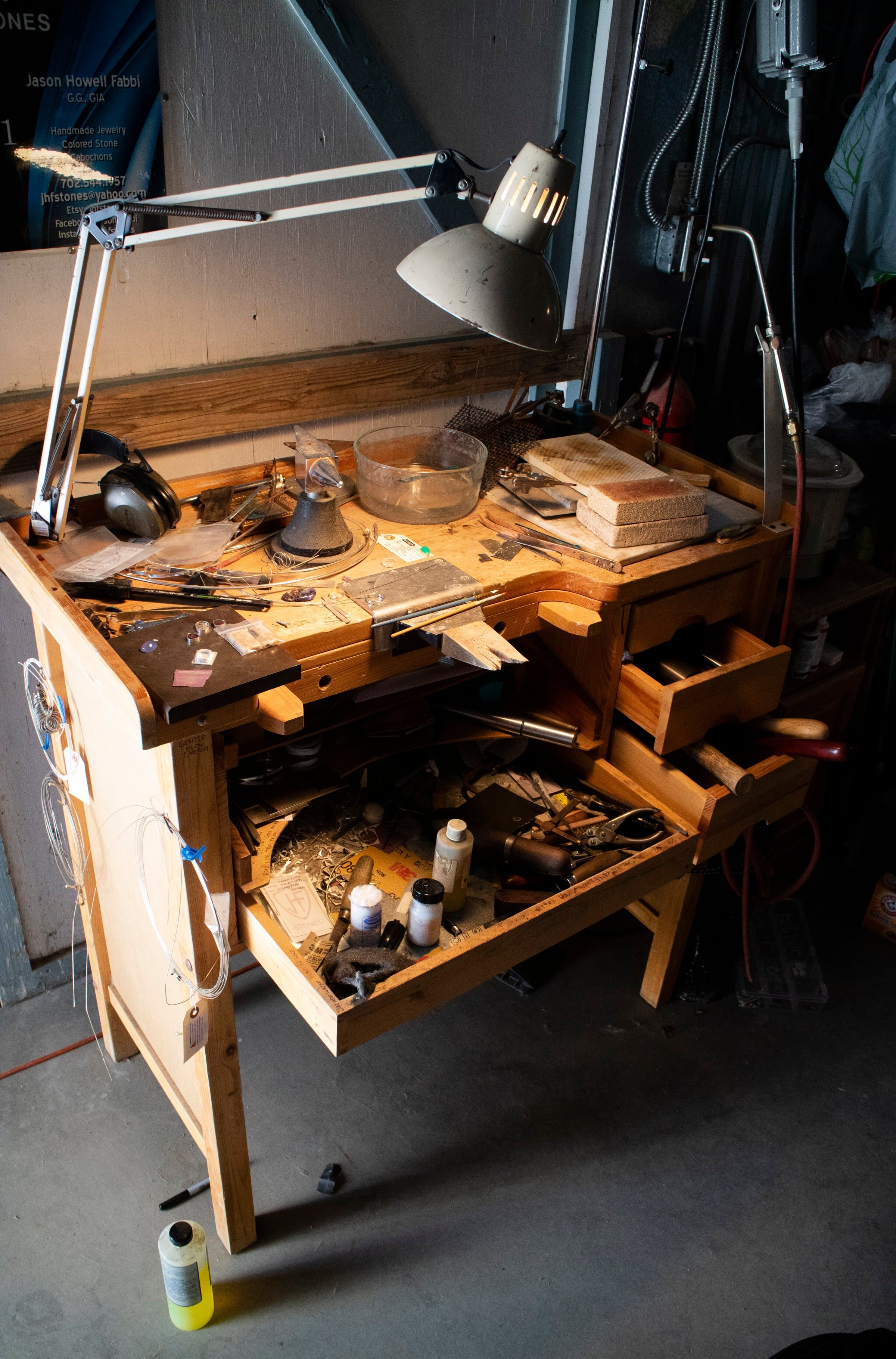 A jeweller’s workbench with hand tools laid out under a lamp
